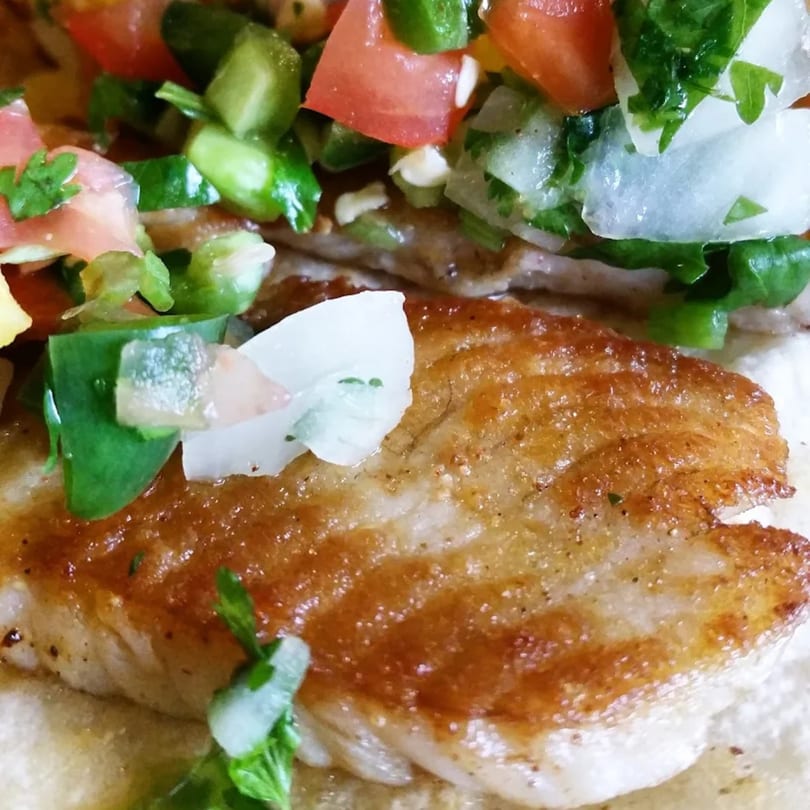 Close-up of a La Esperanza fish taco with grilled fish, pico de gallo, and onions.