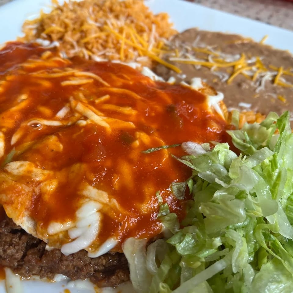 La Esperanza's Mexican dish with enchiladas, rice, refried beans, and fresh lettuce.