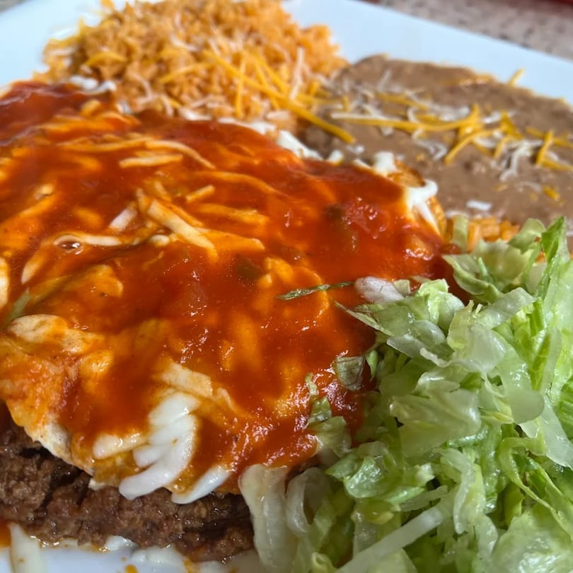 La Esperanza's Mexican dish with enchiladas, rice, refried beans, and fresh lettuce.